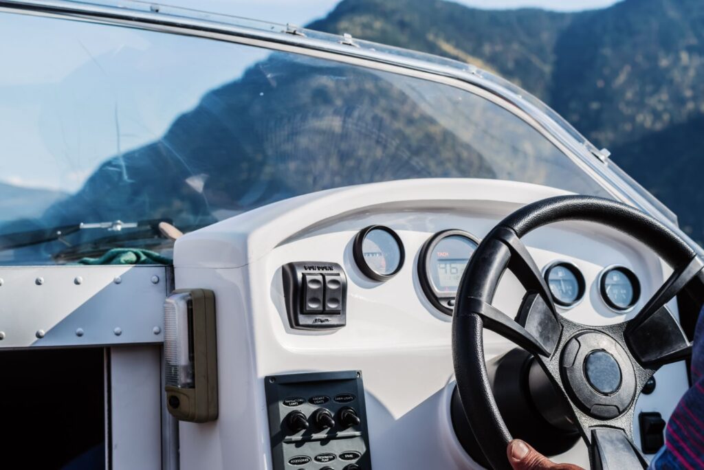 Steering Wheel, Dashboard, And Glass Windshield Of A Motor Boat.